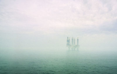 A jack- up oil rig emerging from the mist. 