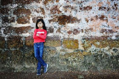 Full length portrait of woman standing against wall