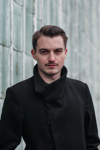 Portrait of young man standing against wall