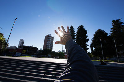 Midsection of person with arms raised against sky