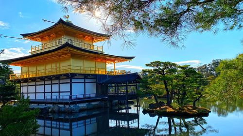 Traditional building by lake against sky