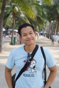 Portrait of smiling young man standing on footpath 