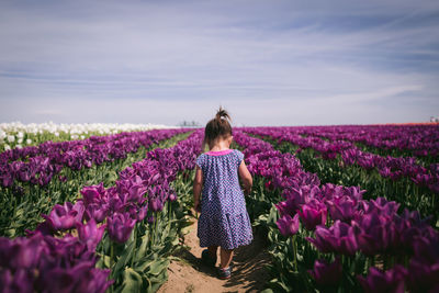 Rear view of woman standing on field against sky