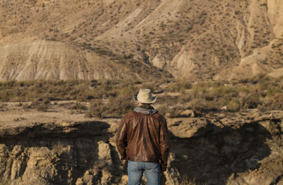 Rear view of adult man in cowboy hat looking at view of tabernas desert, almeria, spain