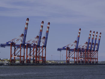 Cranes at commercial dock against sky