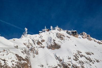 Low angle view of snowcapped mountain against blue sky