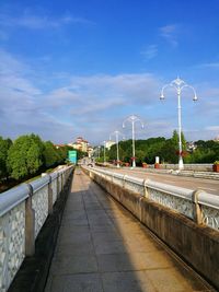 Footpath by street against sky