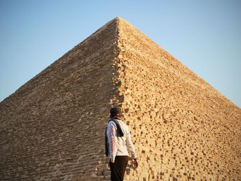 Full length rear view of man walking in desert against clear sky