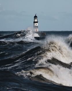 Lighthouse in sea against sky