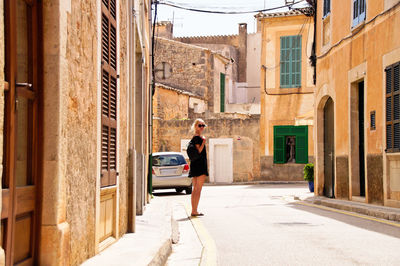 Man standing on street amidst buildings in city