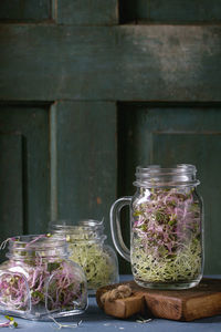 Close-up of bean sprouts in jars on table against door