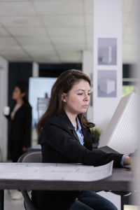 Portrait of young businesswoman using laptop at office