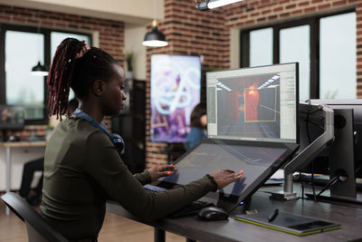 Side view of young woman using computer at office