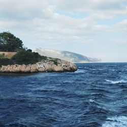 Scenic view of sea and mountains against cloudy sky