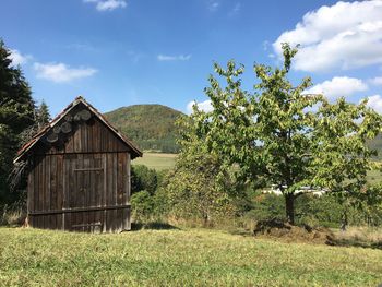 Built structure on field by trees against sky