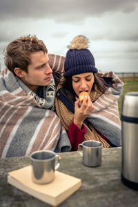 Young woman with man eating muffin