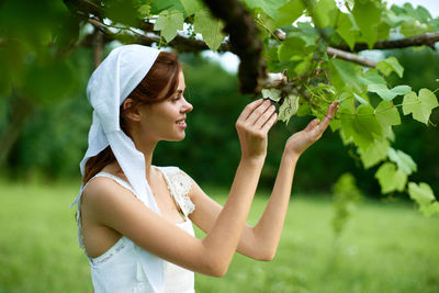 Side view of young woman holding flower