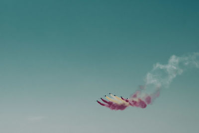 Low angle view of airplanes flying against blue sky