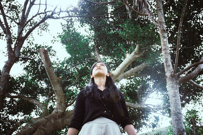 Low angle view of woman sitting in forest