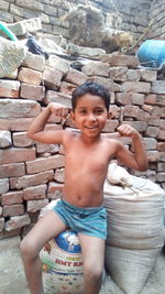 Portrait of shirtless boy with arms raised