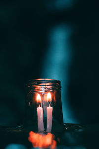 Close-up of burning candles in jar