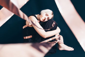 Portrait of woman tied with ribbon against black background