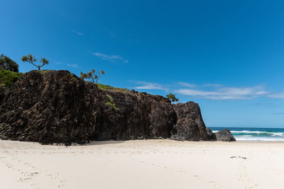 Rock formations on beach against blue sky