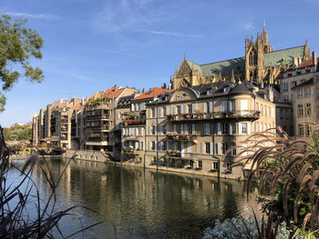 Buildings by river in town against sky