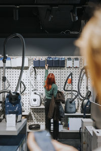 Rear view of female customer examining appliances while shopping in modern electronics store