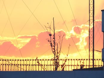 Silhouette of electricity pylon against sky during sunset