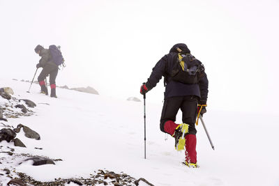 People skiing on snowcapped mountain against sky