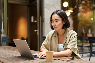 Young businesswoman using laptop while sitting on table