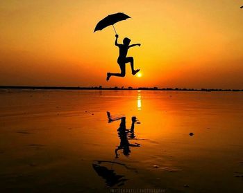 Silhouette of man on beach against sky during sunset