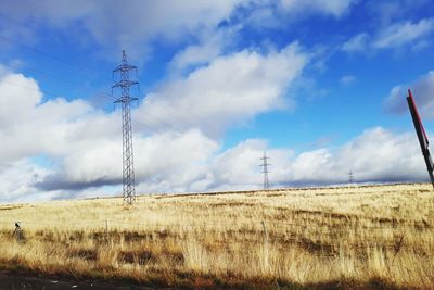 Electricity pylon on field against sky