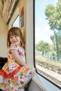 Cute girl standing by window in train