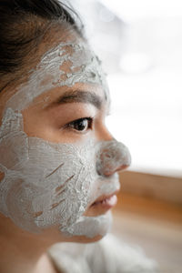 Close-up of woman with facial mask looking away