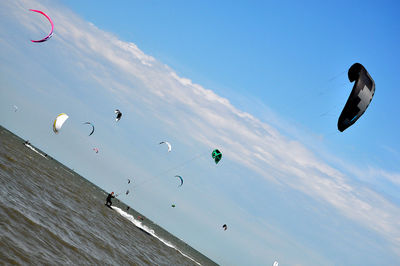 People paragliding at beach against sky