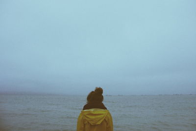 Rear view of woman standing by sea against sky