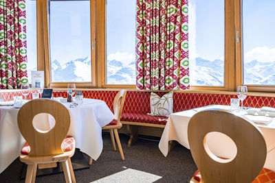 Elegant table setting beside window in hotel against snowcapped mountains