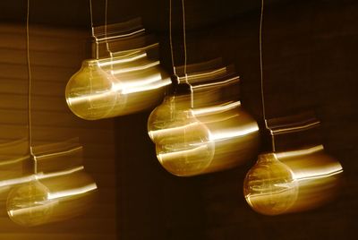 Close-up of illuminated light bulbs hanging from ceiling