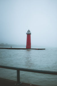 Lighthouse by sea against sky