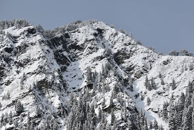 Low angle view of snowcapped mountains against clear sky