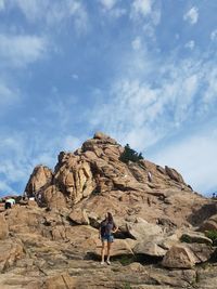 Rear view of person on rock formation against sky