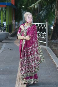 Woman in traditional clothing standing on footpath