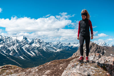 Full length of young woman standing on mountain against sky