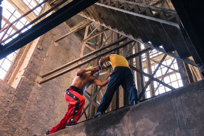 Low angle view of men boxing at construction site