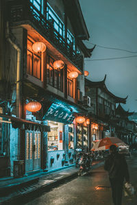 Illuminated road by building at night