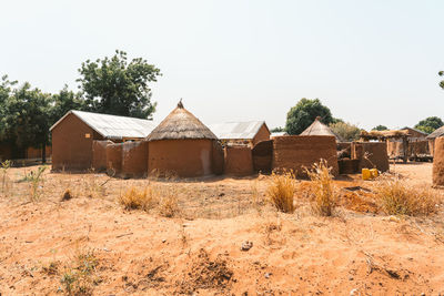 Old house and huts in village against clear sky