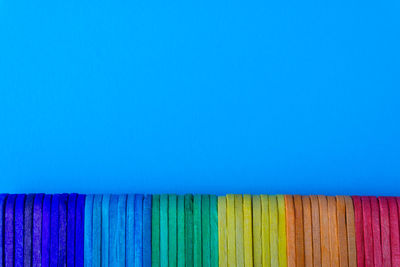 Close-up of multi colored pencils against blue wall