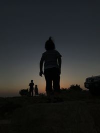 Rear view of silhouette people standing on street against sky during sunset